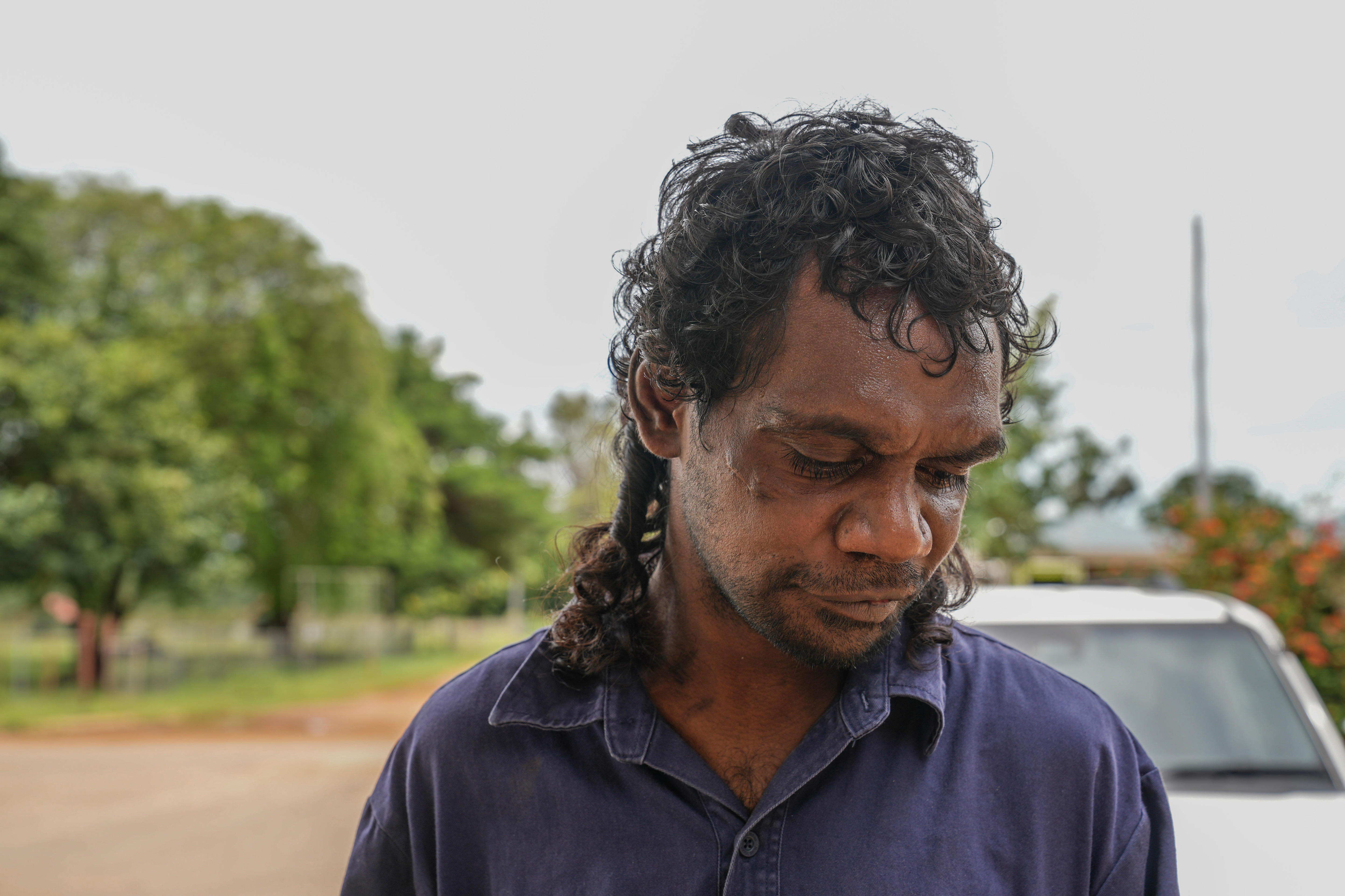 一个留着卷曲鲻鱼头的男人低头看着地面