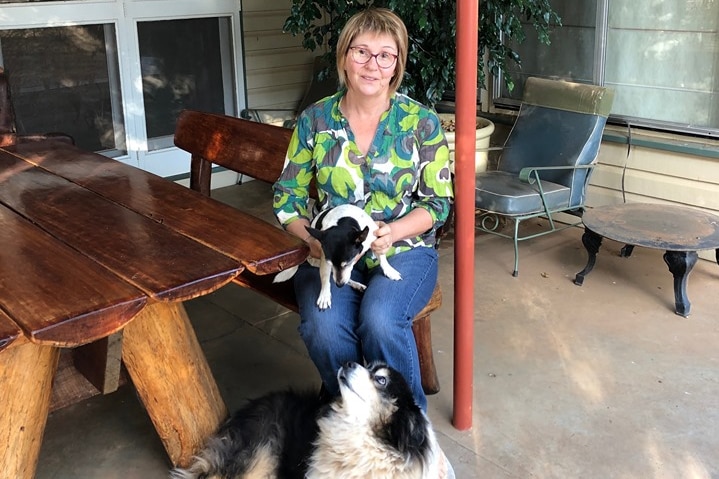 A woman sits on her patio with two dogs