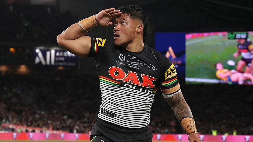 A Penrith NRL player puts his hand to his head as he celebrates scoring a try in the grand final.