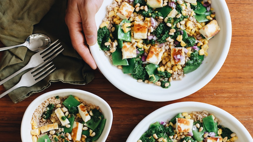 Three bowls of couscous salad with salsa verde, corn and halloumi, two adult bowls and one child serving.