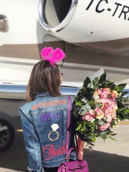 Image of a woman standing next to a plane, wearing a denim jacket with the words #bettertogether and Mrs and Bride