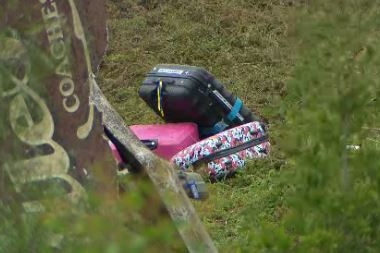 Luggage strewn on an embankment.