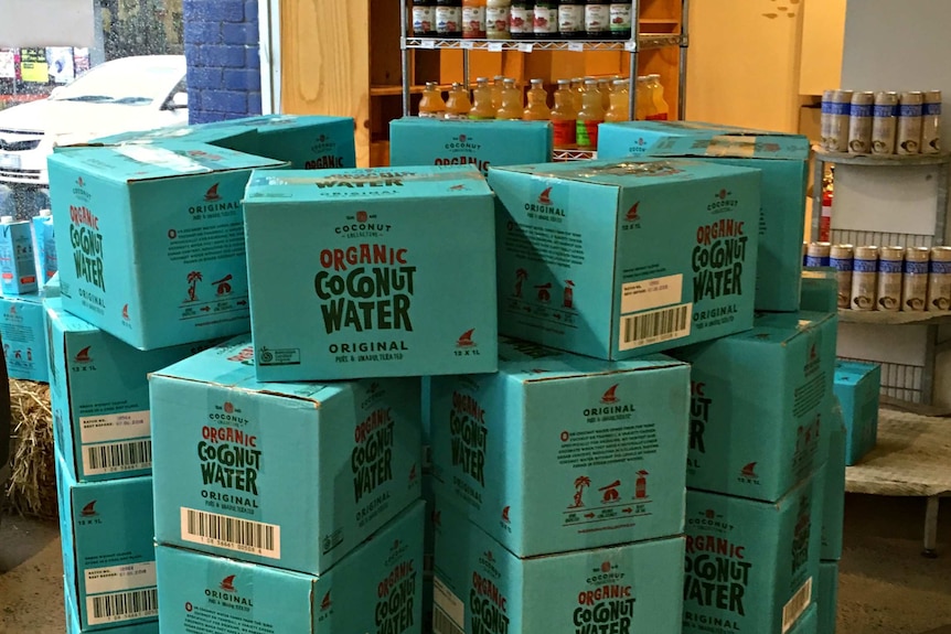 Stack of blue boxes labelled 'organic coconut water' stacked on a shop floor.