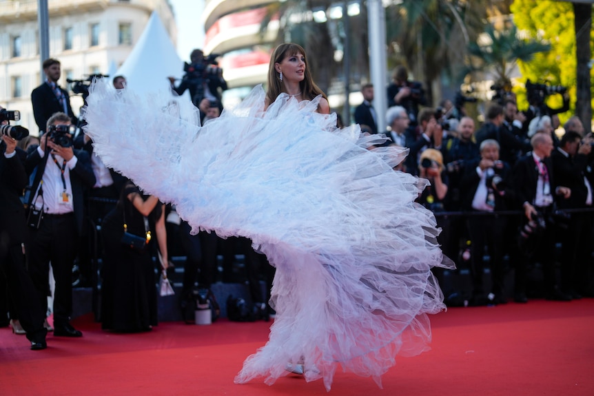 Frederique Bel standing on a red carpet with her light blue train splayed out like a tulle fan. 