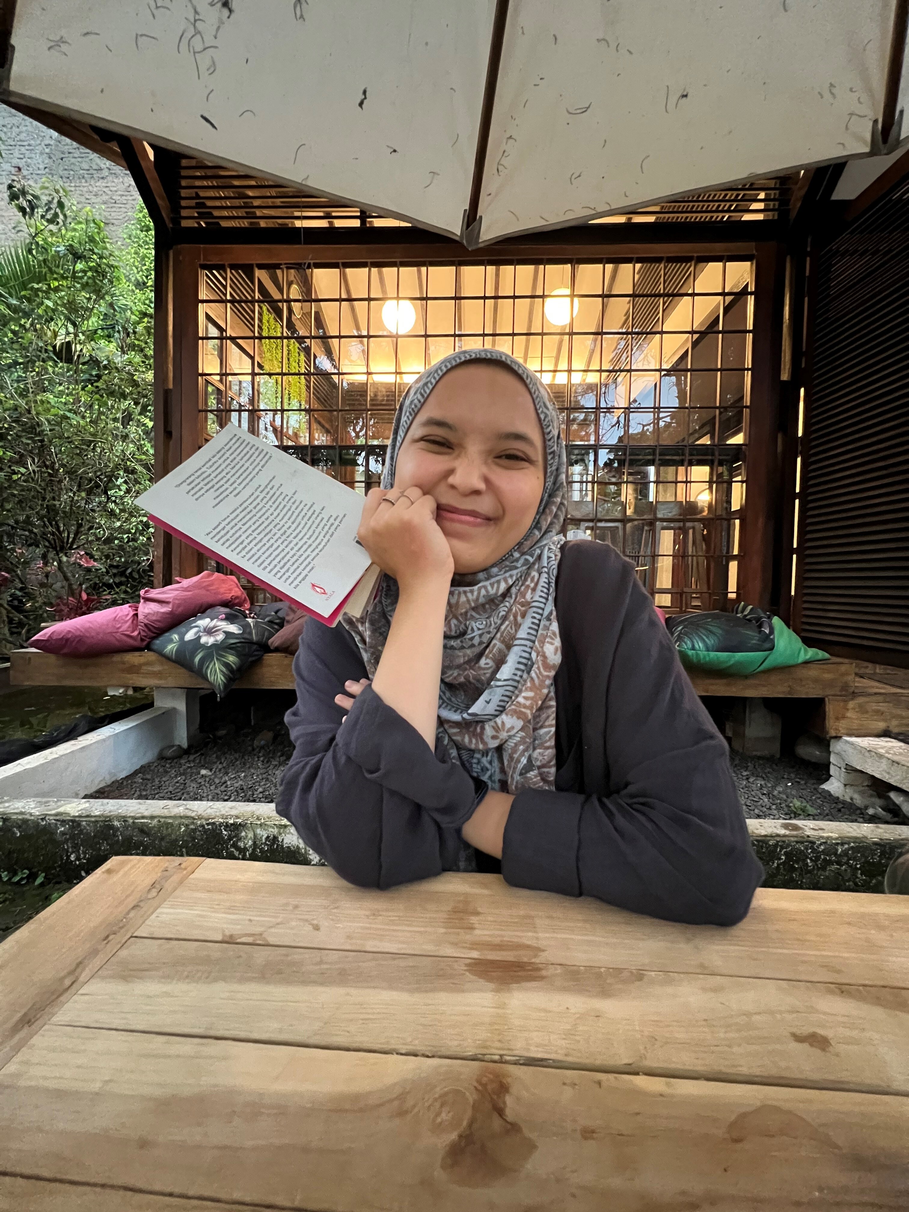 A woman wearing a head cover and smiling to camera
