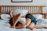 Two women in bed playing with pillows in a story about having sex when you don't feel like it.