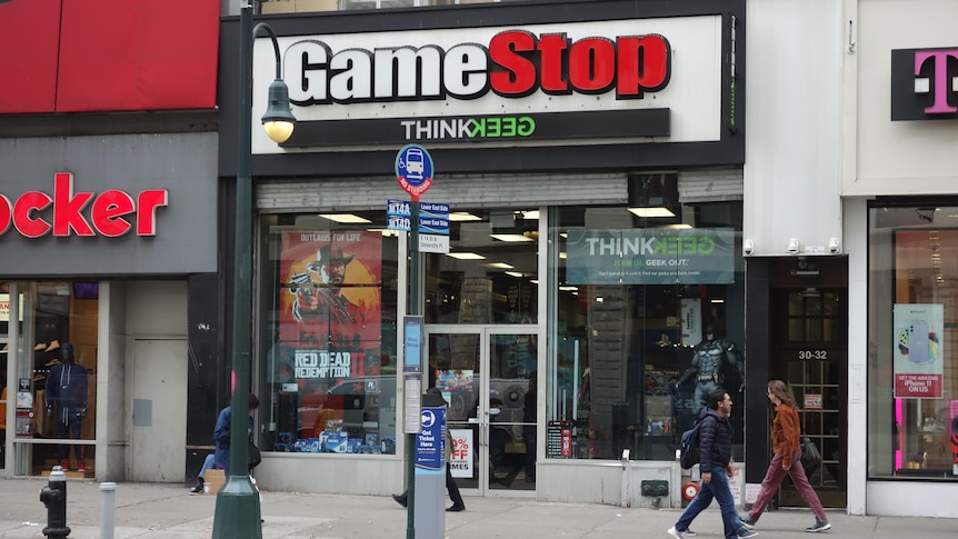 People walk past a GameStop store in Manhattan, New York, in a story about what to know before investing in GameStop GME.
