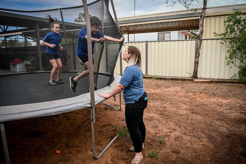 Molly with her two children bouncing on a trampoline