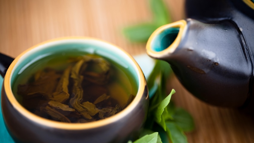 A cup of green tea with a teapot.