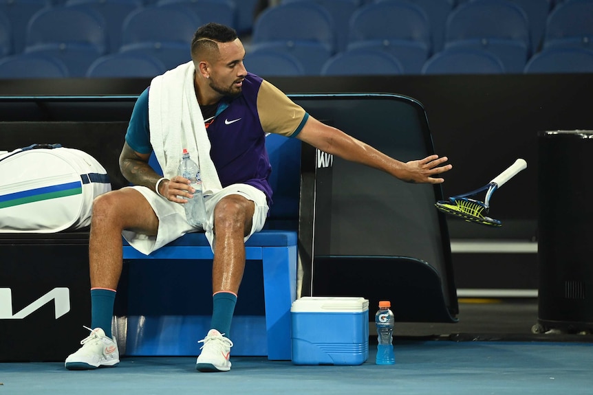 While sitting on his bench with a towel over his shoulder, Nick Kyrgios tosses aside a racquet he has smashed