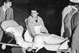 A young woman sits up on a stretcher 