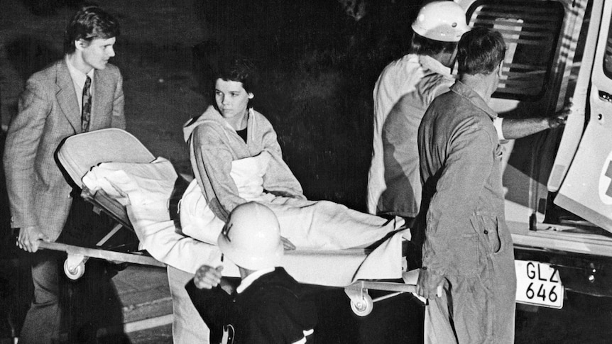 A young woman sits up on a stretcher 