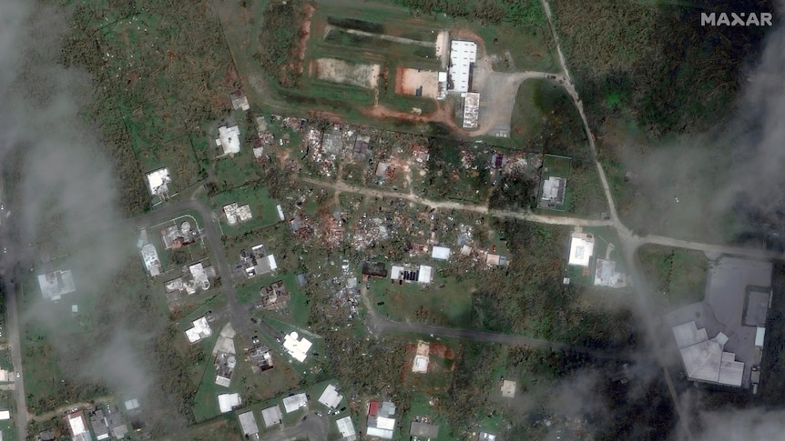 Satellite image of green plains, can see some houses destroyed.