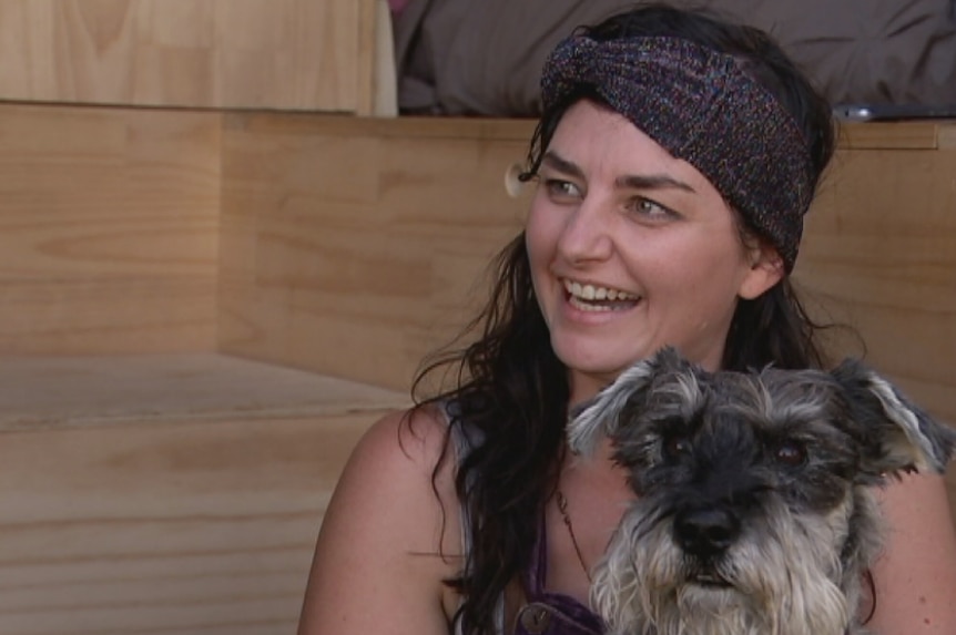 Van lifer, Cristal Cachia sits inside her van holding her dog, Henry, on her lap