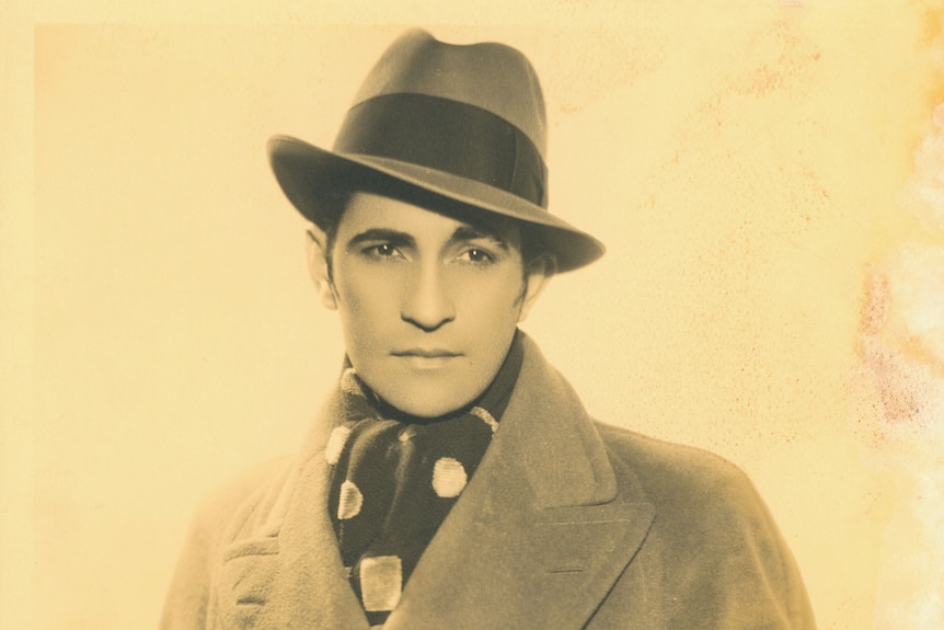 Sepia portrait of an attractive man with dark features in a hat and jacket.