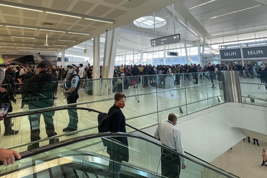 Lines of people stand waiting to get through a security checkpoint at Adelaide Airport