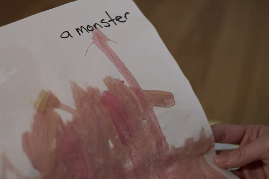 A childish painting in pink and brown paint on paper with the label 'a monster' written at the top.