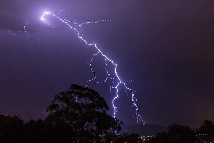 Lightning hits a tower atop a mountain in the distance.