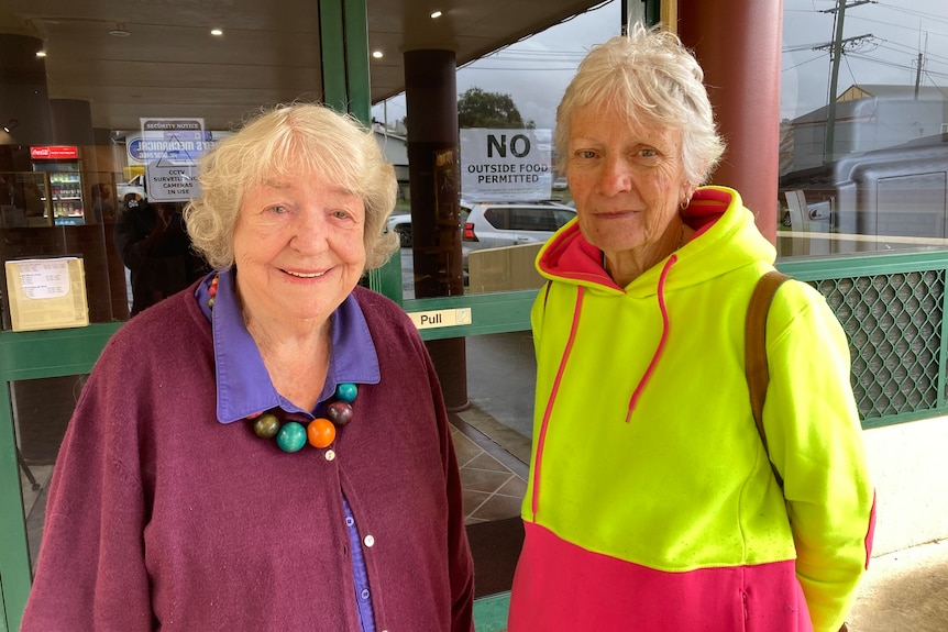 Two women in colourful clothing stand outside a cinema.