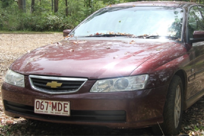 A 2003 maroon Holden Commodore sedan with Queensland registration 067-MDE.