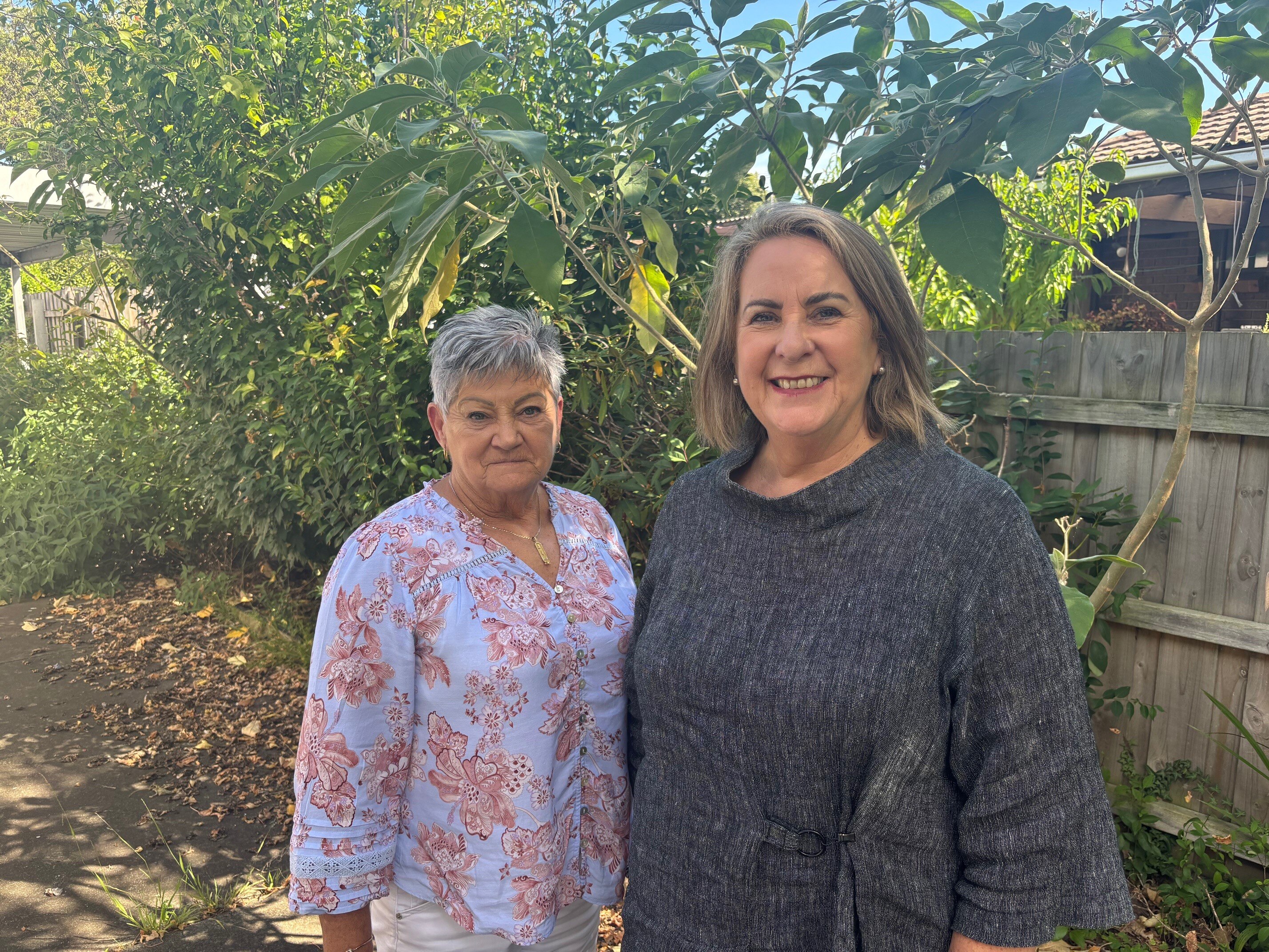 Dos mujeres paradas en el sitio de una cooperativa de vivienda, frente a la cámara. 