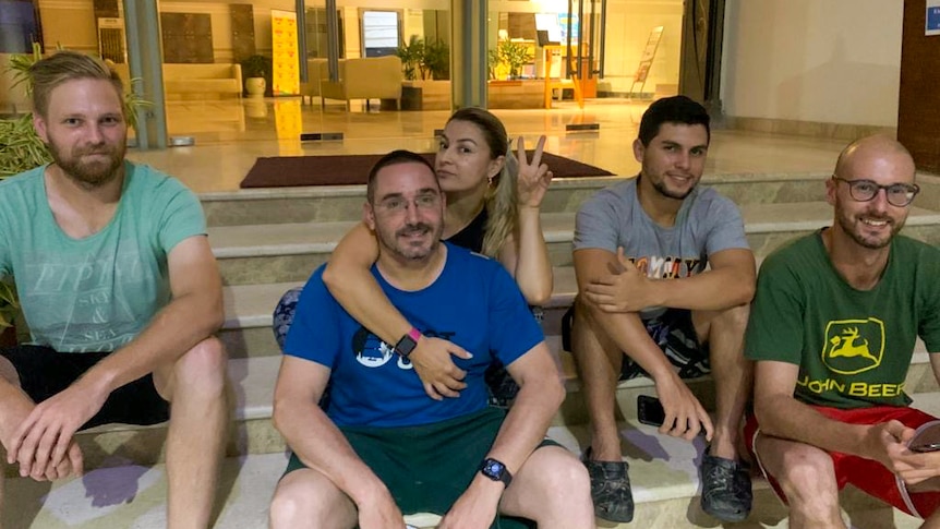 A group of Australians sitting on a set of stairs outside a hotel lobby