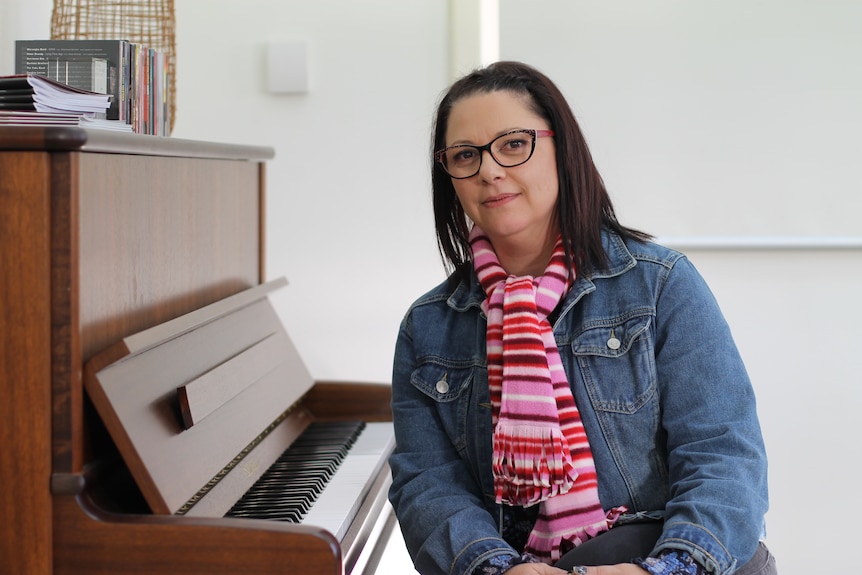 Livia Carre sitting beside upright piano