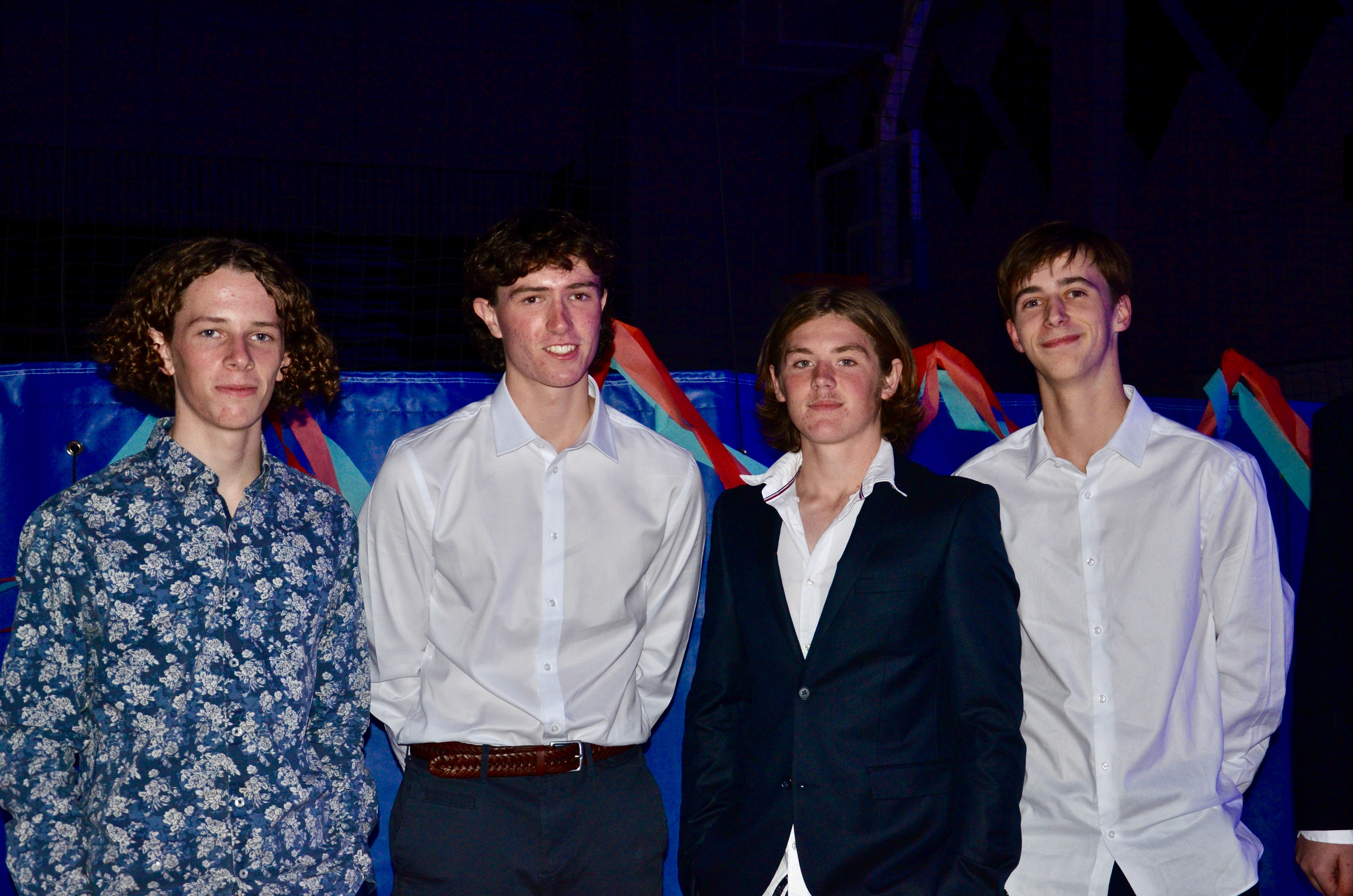 Four young men smile in suits.