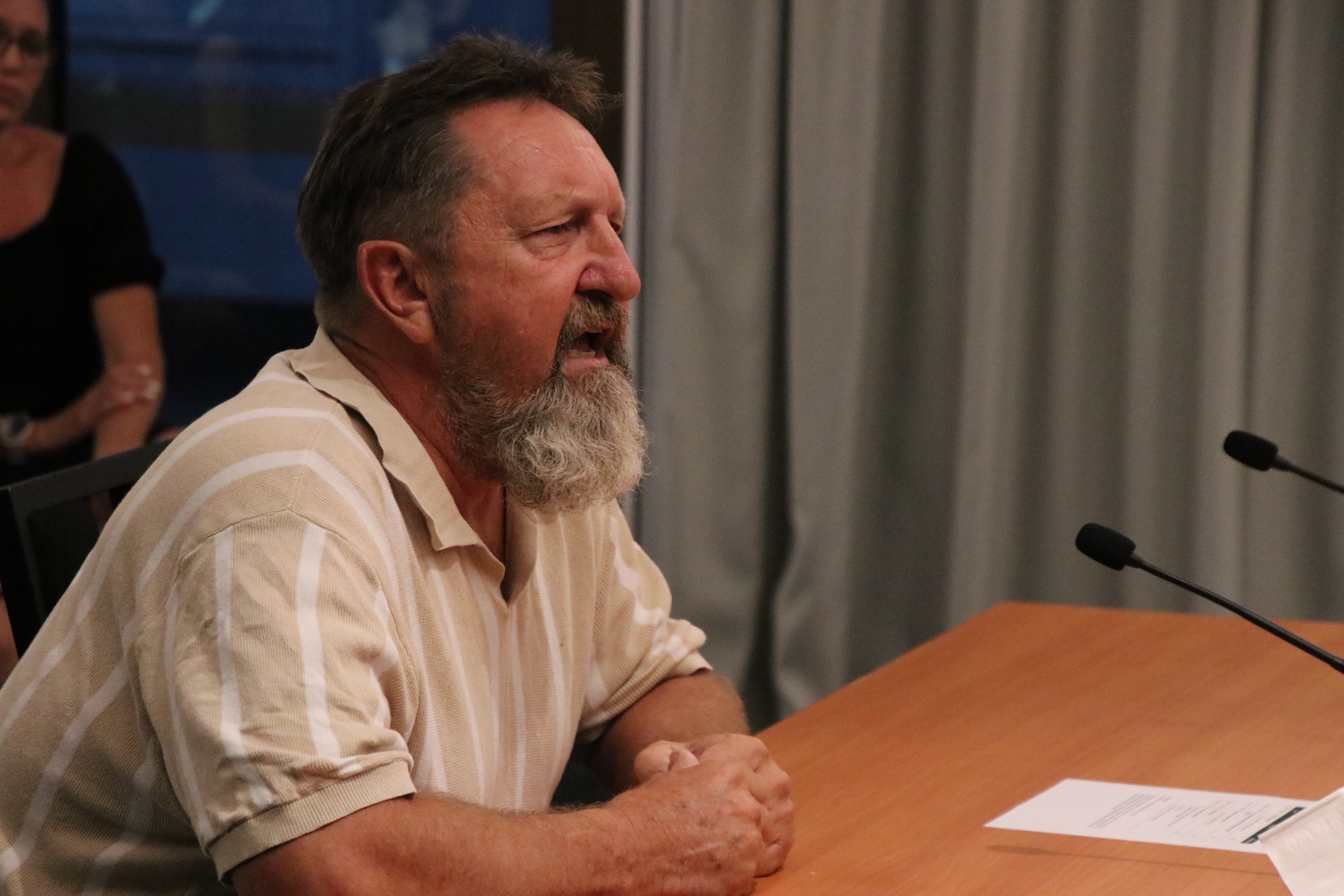 A man sitting at a desk yelling into a microphone.