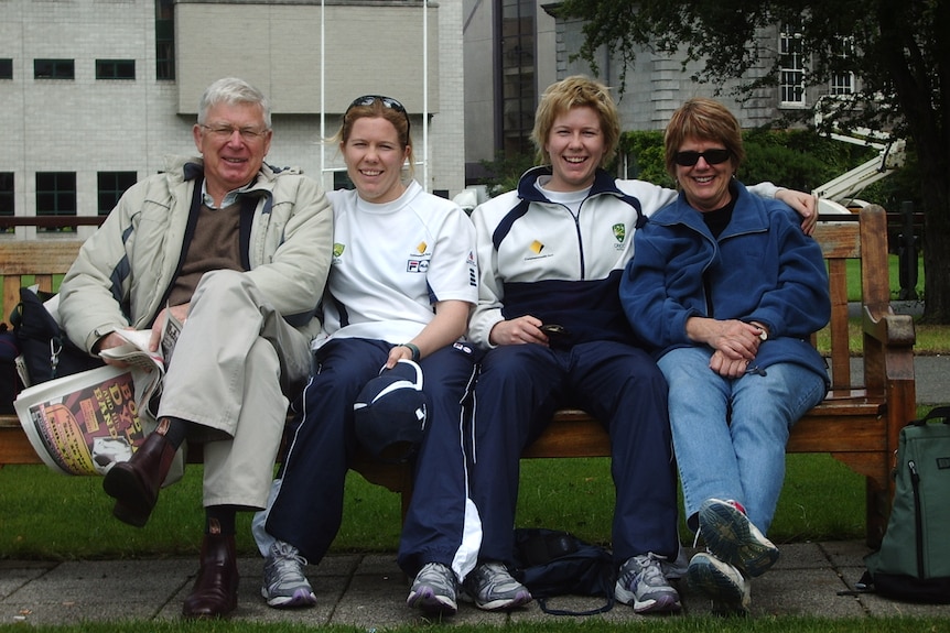 The Blackwell family sit on a bench, they are all looking at the camera and smiling.