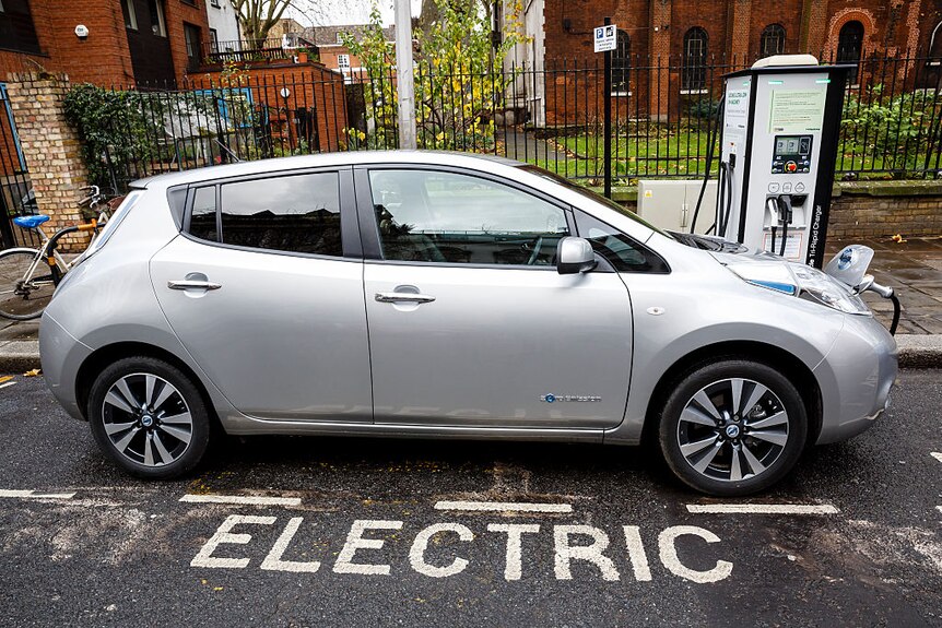 A silver electric car plugged in to charge.