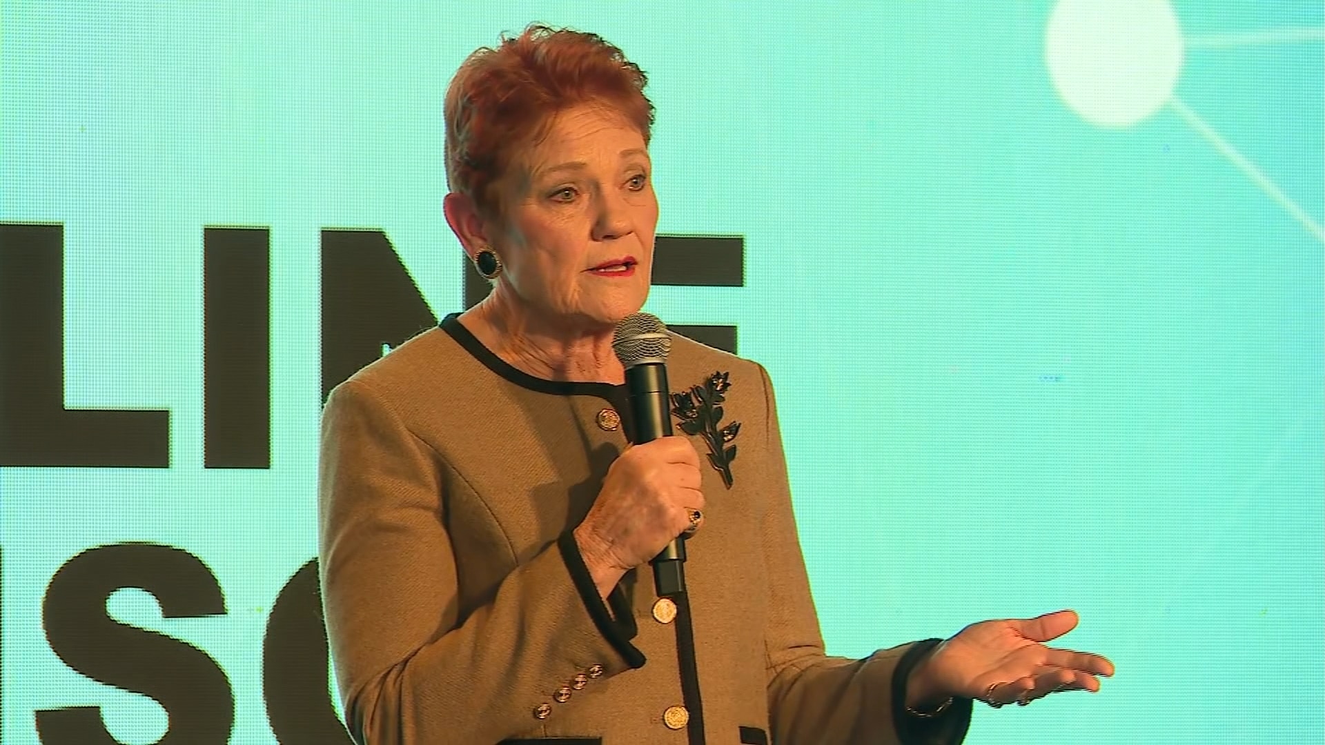 Pauline Hanson speaking into microphone at a conference.