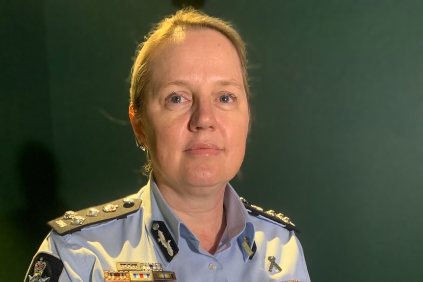 A woman in a light blue police uniform holding her hands together in front of herself