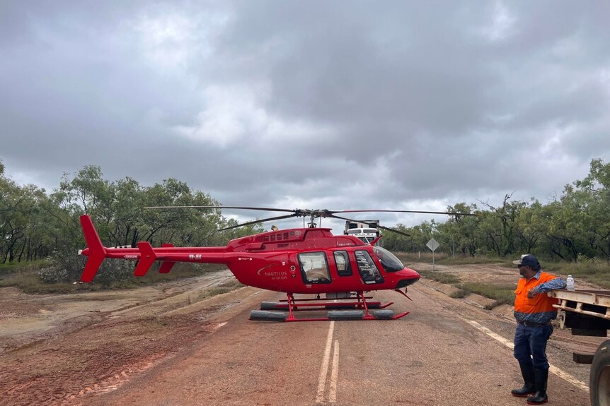 A red helicopter parked on a road .