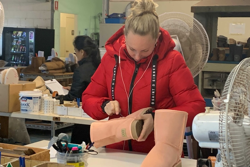 Ugg boot factory at Burleigh Heads Gold coast and worker putting finishing touches to making salmon coloured boot