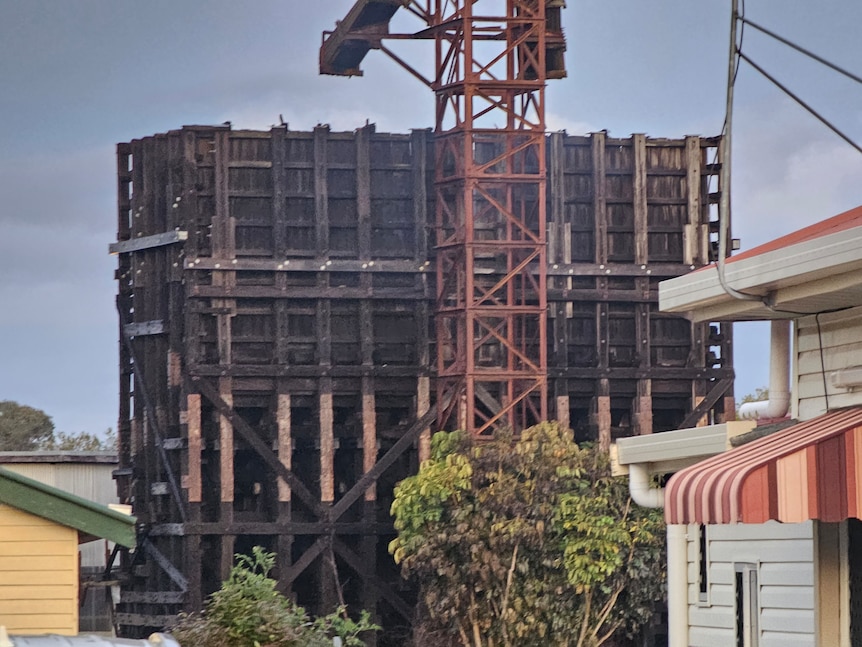 A large timber structure is burnt and is pictured close to houses