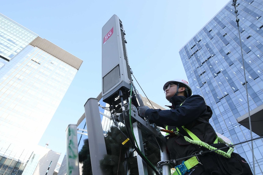 A technician checks an antenna for the 5G mobile network service