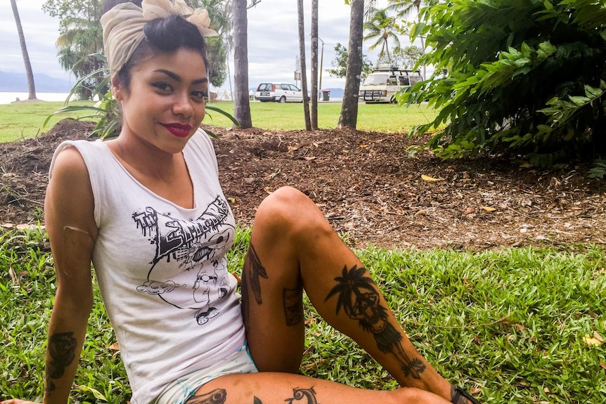 Tattooed young woman relaxes on grass