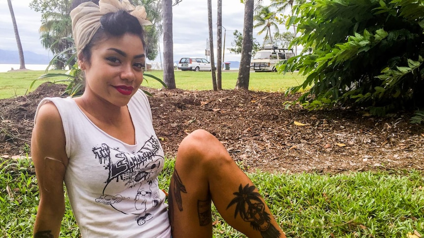 Tattooed young woman relaxes on grass