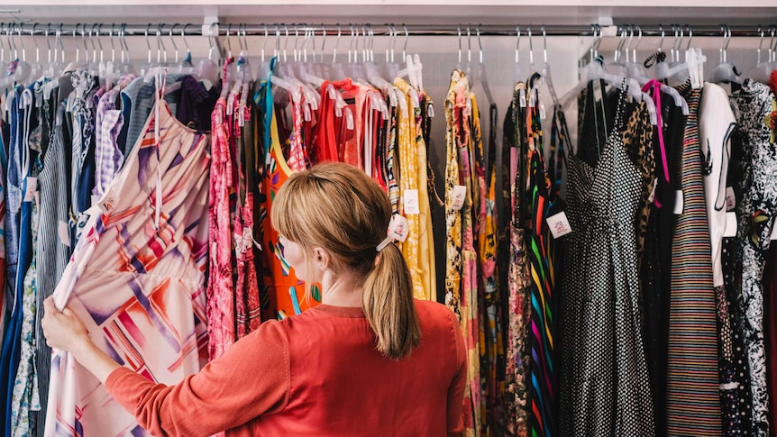 Woman looking at dress hanging on rack while standing at store