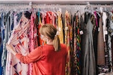 Woman looking at dress hanging on rack while standing at store