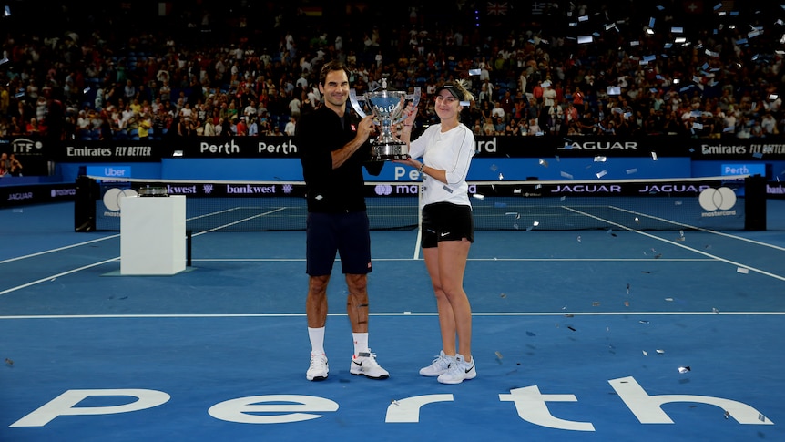 Roger Federer and Belinda Bencic of Switzerland hold up the Hopman Cup in Perth
