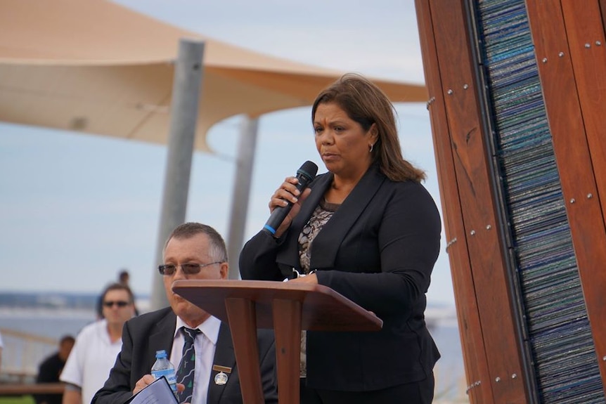 An Aboriginal woman speaking behind a podium.