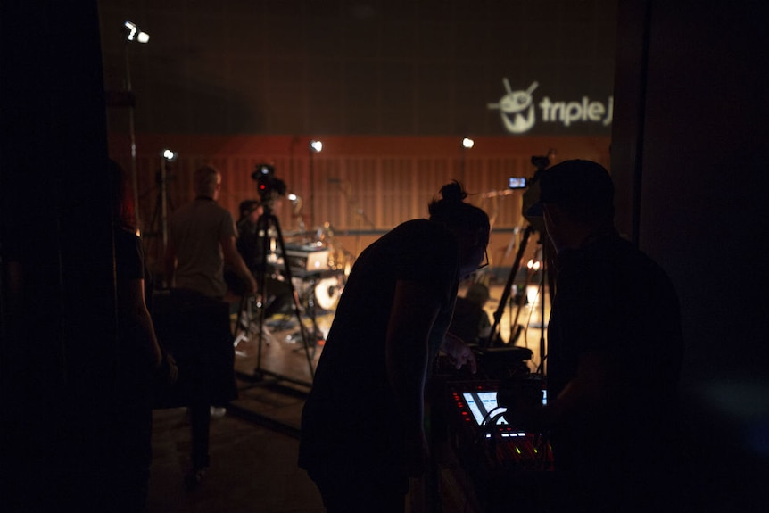 A shot of the audio team checking levels and cameras in the background of a studio.