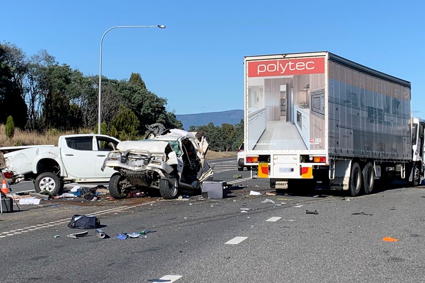 Two crumpled cars, a truck and a motorbike smashed to the highway in front of the truck.