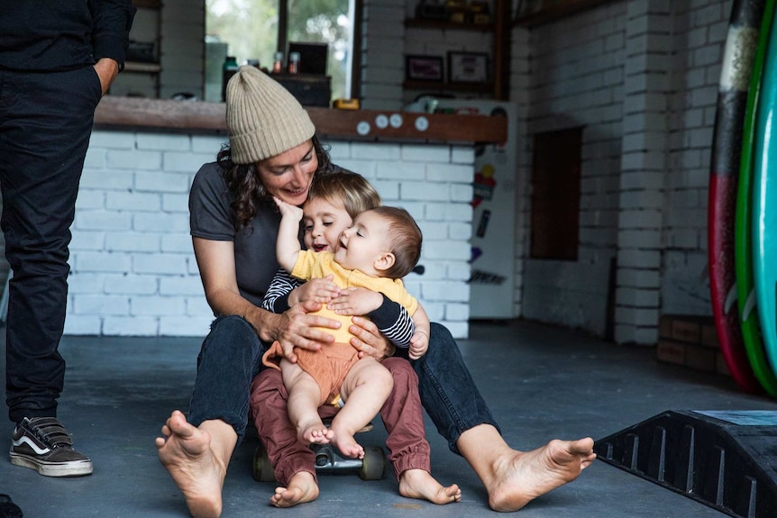 Milenka playing with her two kids on a skateboard.