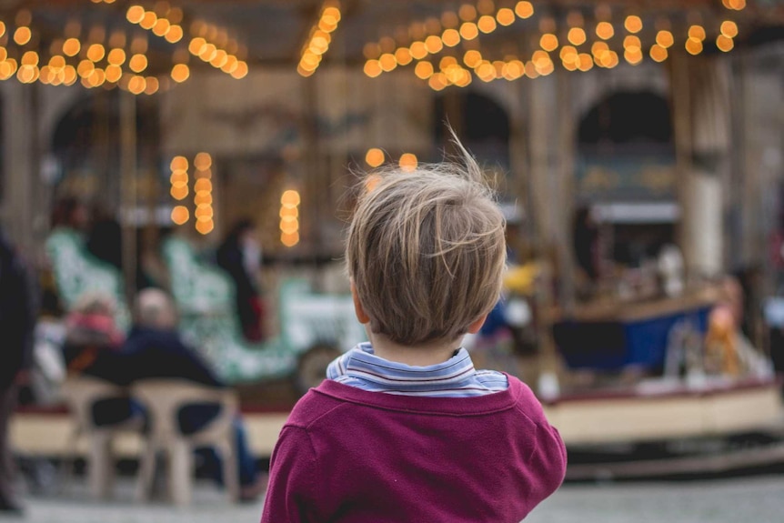 Little boy looks at merry-go-round