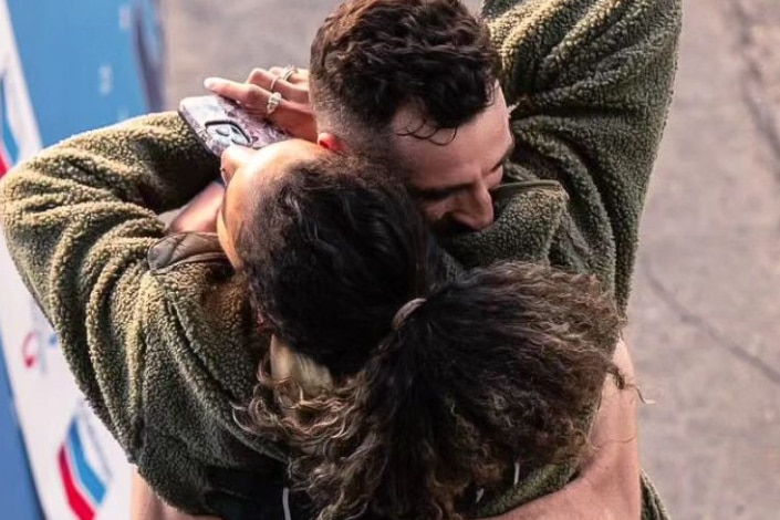 A runner hugs his wife at the finish of a race
