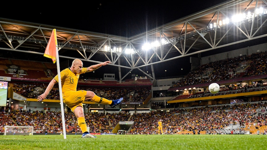 Aaron Mooy follow through after taking a corner with Lang Park in the backdrop