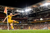 Aaron Mooy follow through after taking a corner with Lang Park in the backdrop